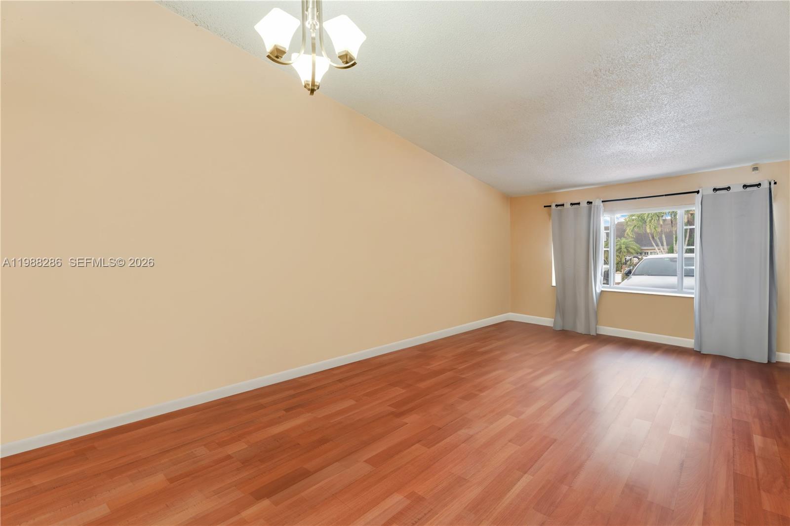 An empty room features light-colored walls, wood-look flooring, a ceiling light fixture, and a window — 7821 SW 148th Ave # 2, Miami FL 33193, MIAMI, FL