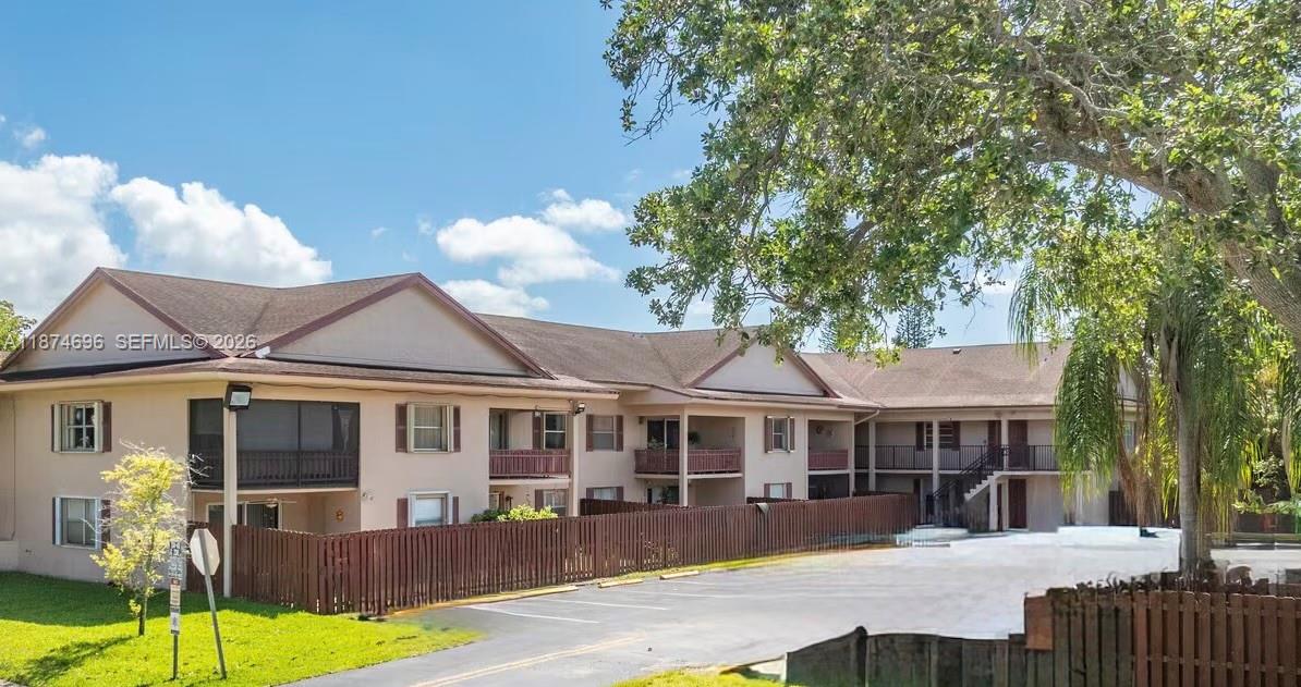 A two-story apartment building with a parking lot and a wooden fence in front — 11295 SW 88th St # M109, Miami FL 33176, MIAMI, FL