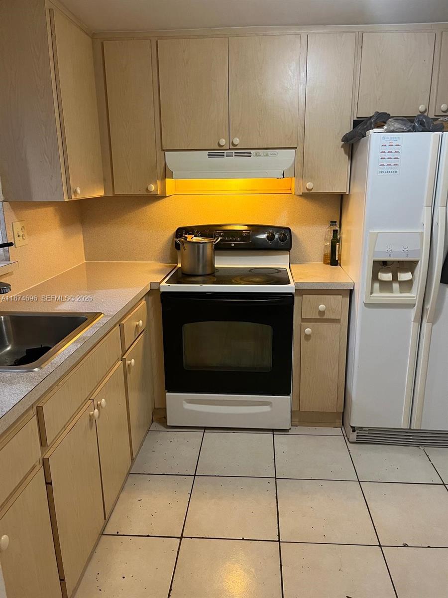 A kitchen features light wood cabinets, a black electric stove, and a white refrigerator — 11295 SW 88th St # M109, Miami FL 33176, MIAMI, FL