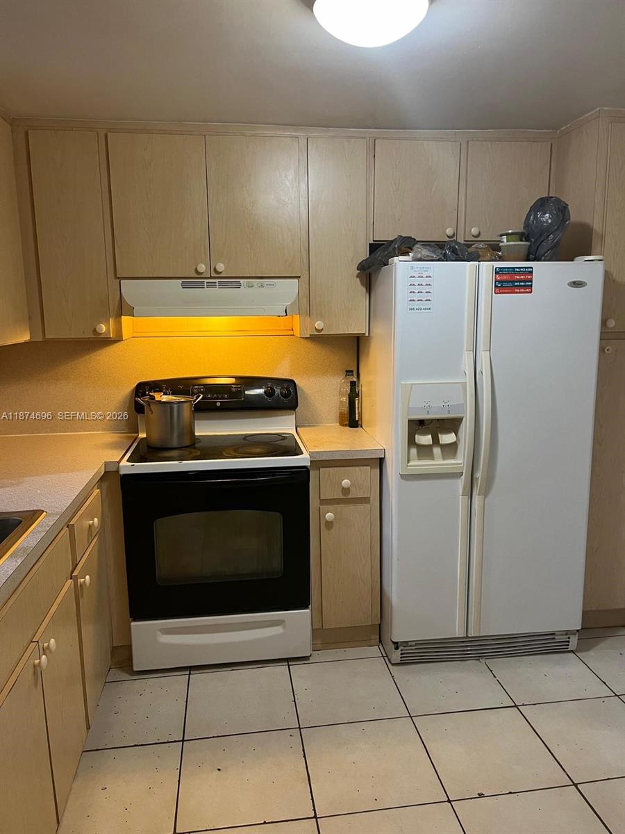 A kitchen features light wood cabinets, a white stove, and a white side-by-side refrigerator — 11295 SW 88th St # M109, Miami FL 33176, MIAMI, FL