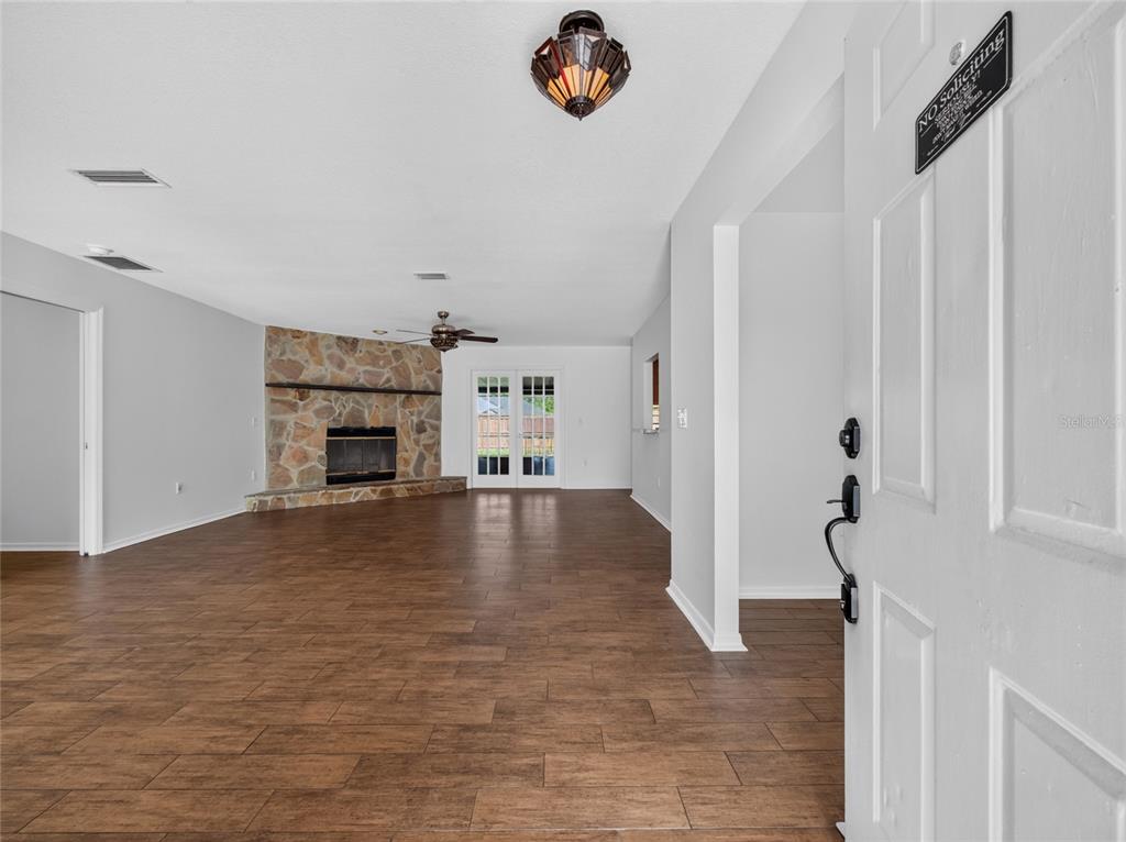 A living room with wood-look tile flooring, a stone fireplace, and a ceiling fan — 811 W HARBOUR COURT, OCOEE, FL