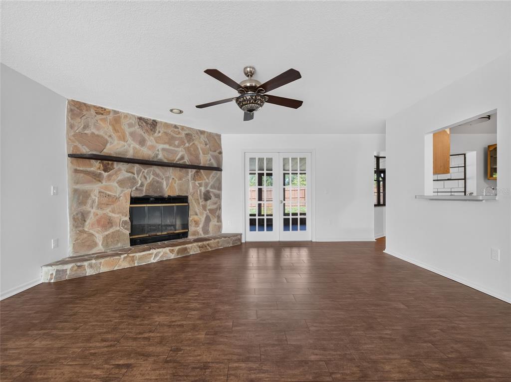 A living room features a stone fireplace, wood-look tile flooring, and white French doors — 811 W HARBOUR COURT, OCOEE, FL