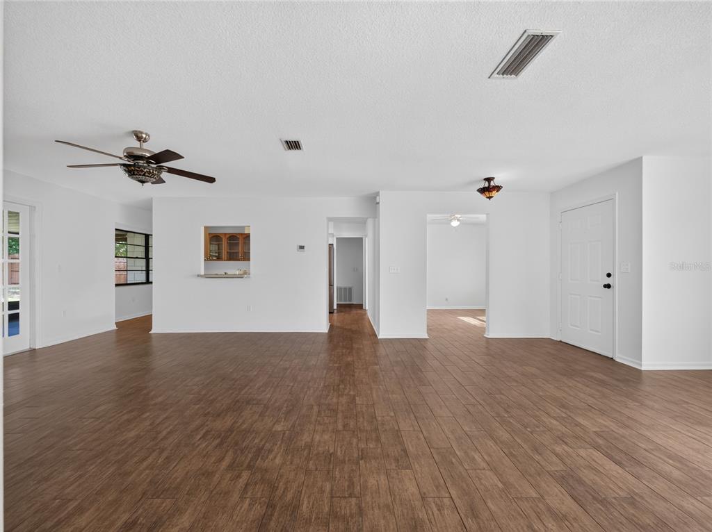 A spacious room with wood-look tile flooring, white walls, a ceiling fan, and multiple doorways — 811 W HARBOUR COURT, OCOEE, FL