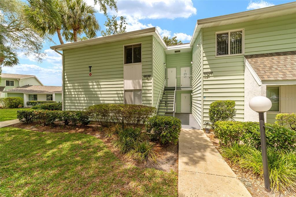 A two-story light green apartment building with a staircase leading to upper-level units — 557 MIDWAY DRIVE UNIT B, OCALA, FL