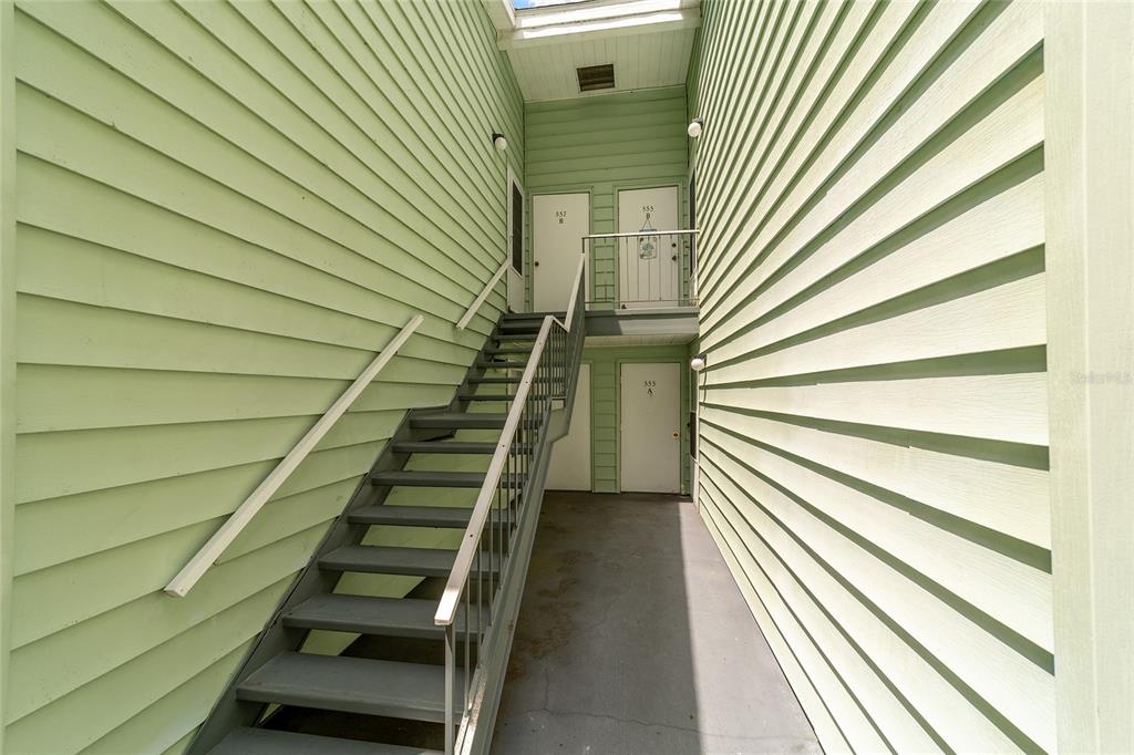 An exterior view of an apartment building staircase leading to upper and lower level doors — 557 MIDWAY DRIVE UNIT B, OCALA, FL