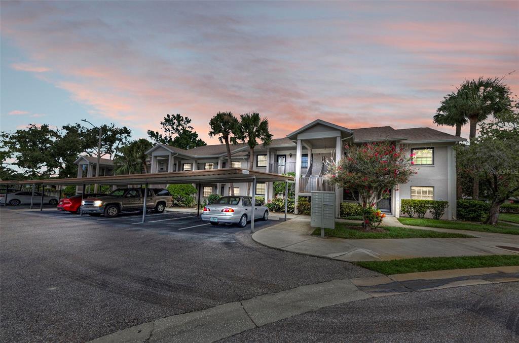 A two-story apartment building with a covered parking area and a paved driveway at sunset — 2119 ELM STREET UNIT 103, DUNEDIN, FL