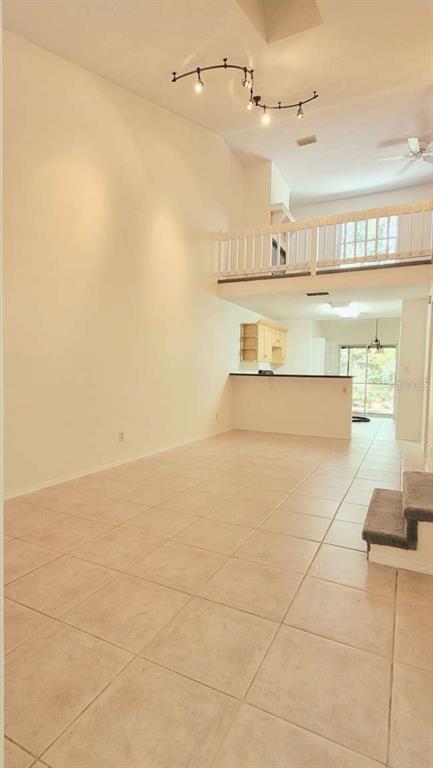 A high-ceilinged living room with light tile floors, a loft balcony, and track lighting — 5801 RED CEDAR LANE, TAMPA, FL