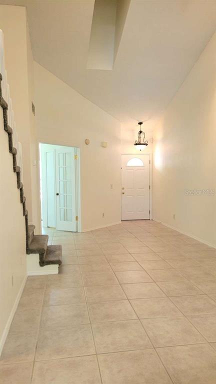 A bright, tiled entryway features a vaulted ceiling, a staircase, and a white front door — 5801 RED CEDAR LANE, TAMPA, FL
