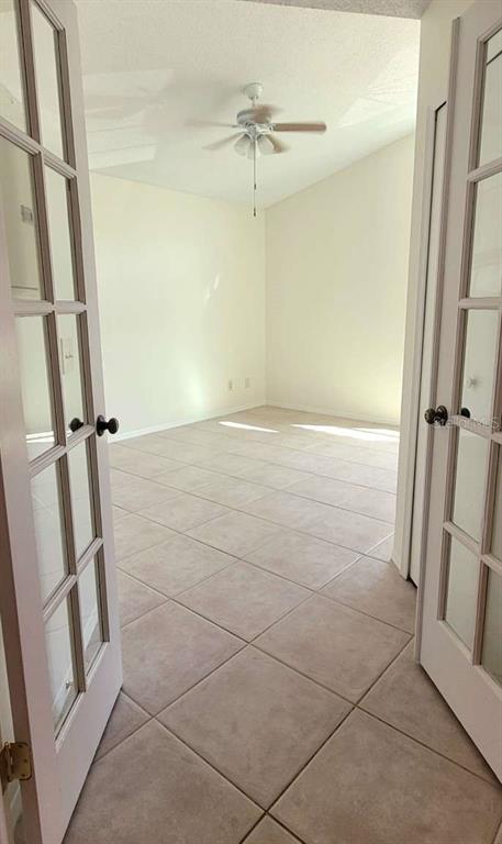 A room with light-colored tile flooring and a ceiling fan is viewed through French doors — 5801 RED CEDAR LANE, TAMPA, FL