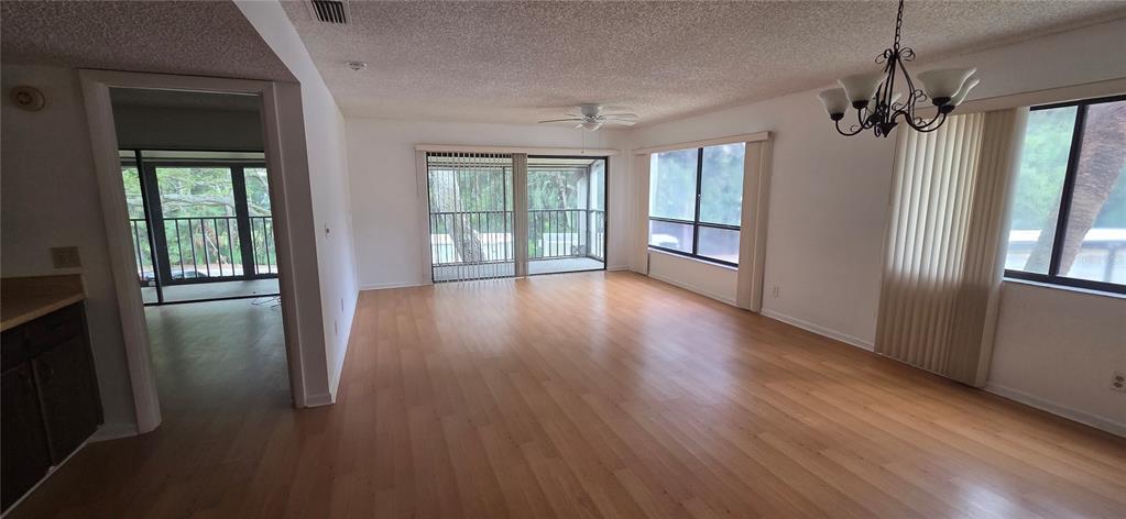 An empty living room with light wood flooring, a ceiling fan, and sliding glass doors — 700 STARKEY RD UNIT 1224, LARGO, FL
