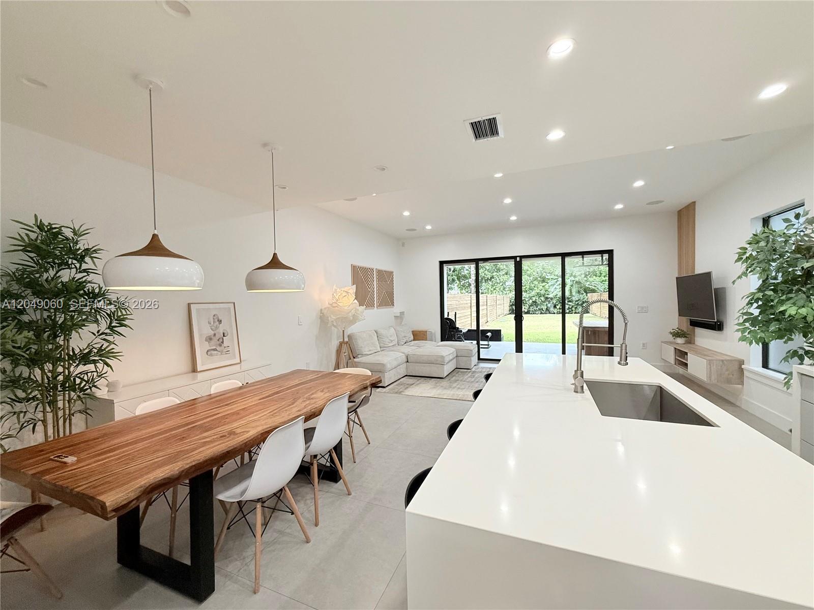 A modern open-concept kitchen and dining area features a live-edge table and large island — 8871 SW 28th St, Miami FL 33165, MIAMI, FL