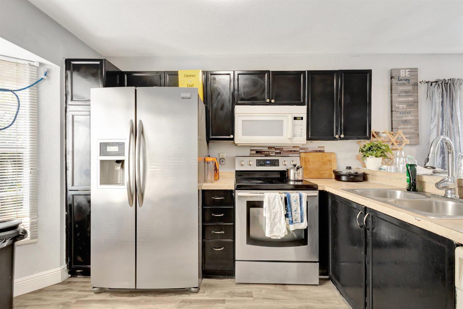 A kitchen with black cabinets, stainless steel appliances, and light-colored countertops — 87 Pheasant Run Boulevard, West Palm Beach FL 33415, WEST PALM BEACH, FL