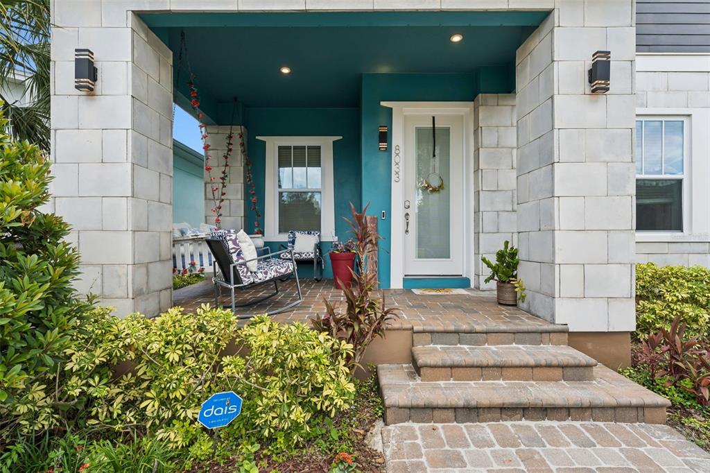 A front porch with a teal ceiling, stone columns, and a white front door — 8033 NEMOURS PARKWAY, ORLANDO, FL