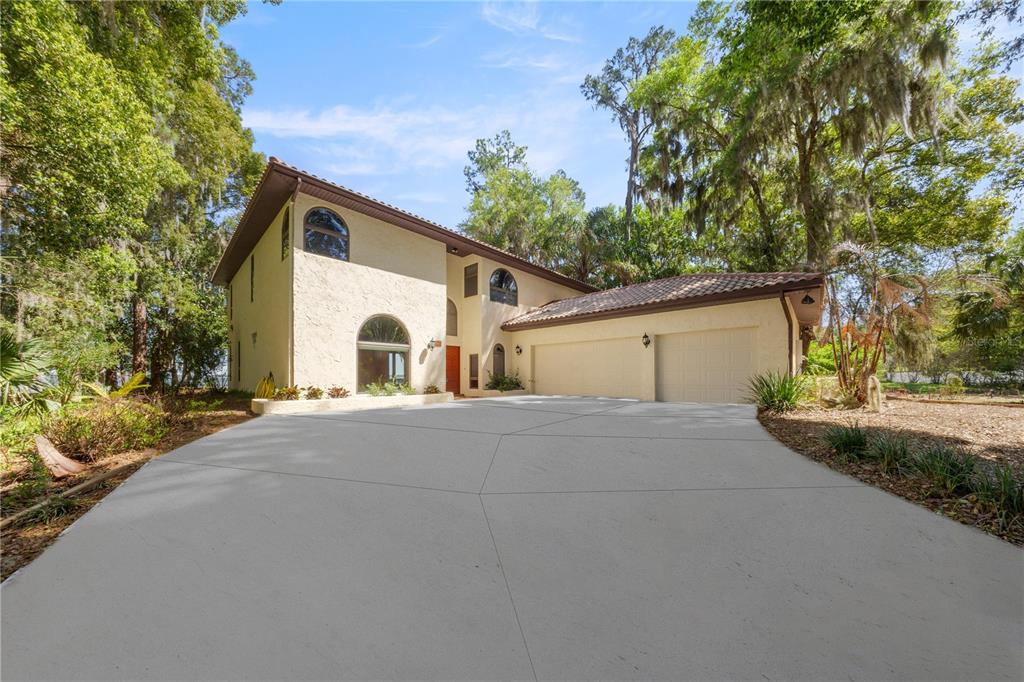 A two-story stucco house with a tile roof and a large concrete driveway — 12621 SE SUNSET HARBOR ROAD, WEIRSDALE, FL