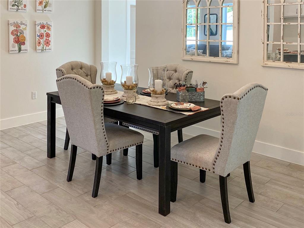 A dining room features a dark wood table with four upholstered chairs and wall art — 904 AZALEA WALK CIRCLE, DELAND, FL
