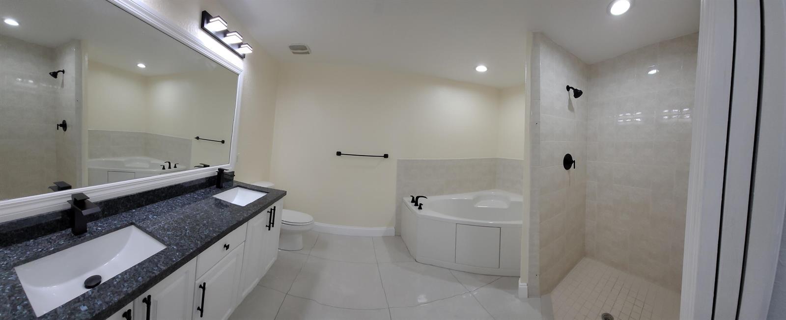 A bathroom features a double vanity with dark countertops, a soaking tub, and a tiled shower — 1772 N Dovetail Drive # C, Fort Pierce FL 34982, FORT PIERCE, FL