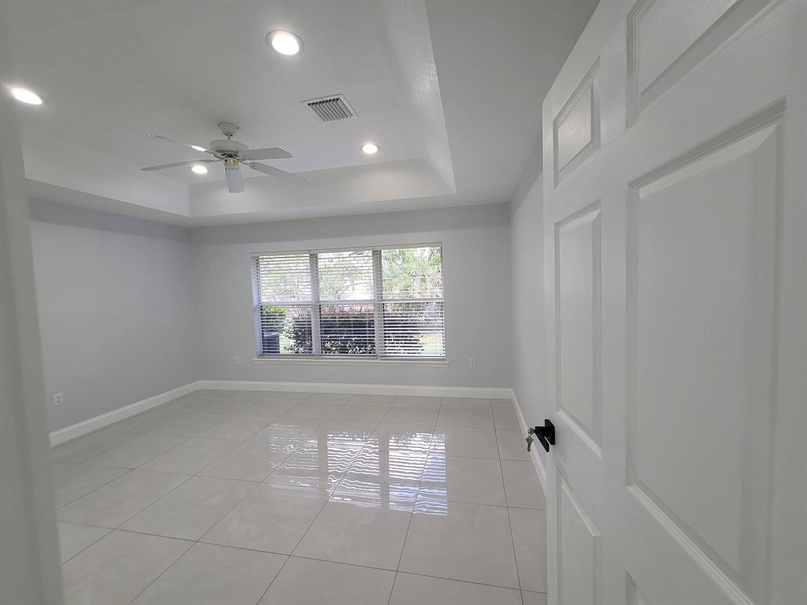 An empty bedroom features light gray walls, large floor tiles, and a tray ceiling — 1772 N Dovetail Drive # C, Fort Pierce FL 34982, FORT PIERCE, FL