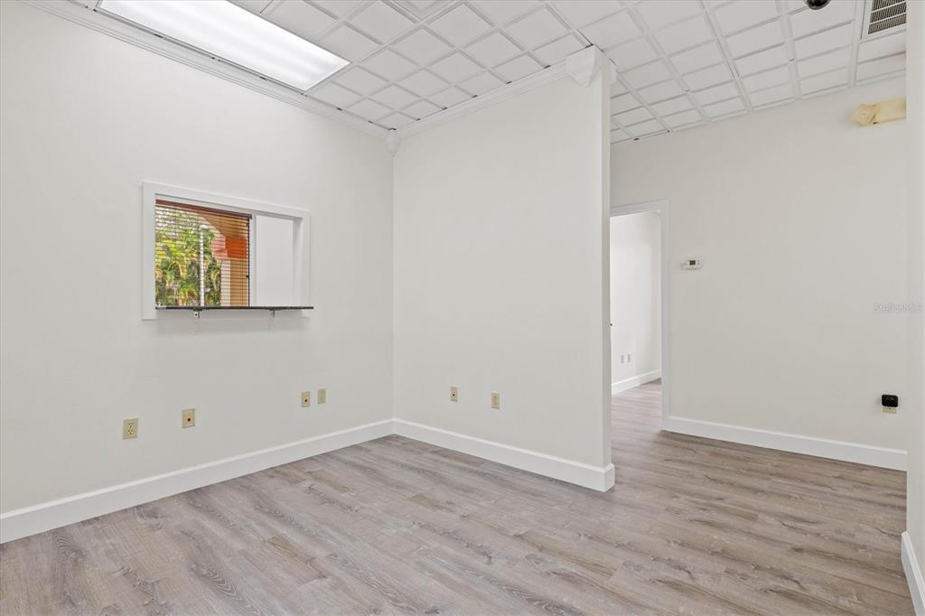 An empty office room features white walls, a drop ceiling, and light-colored wood-look flooring — 234 N RHODES AVENUE UNIT 105, SARASOTA, FL