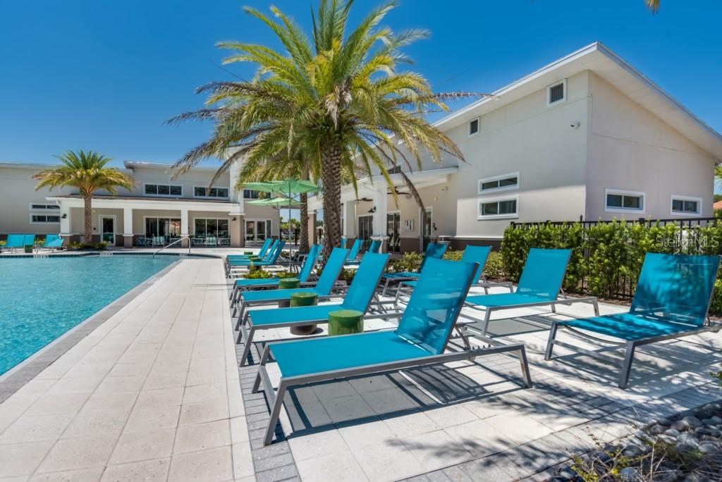A swimming pool with lounge chairs on a patio next to a modern building — 2468 RAMA DRIVE, KISSIMMEE, FL