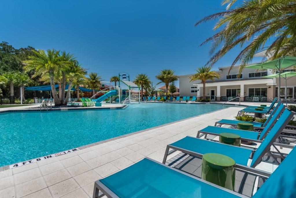 A resort-style swimming pool with lounge chairs, palm trees, and a water slide — 2468 RAMA DRIVE, KISSIMMEE, FL