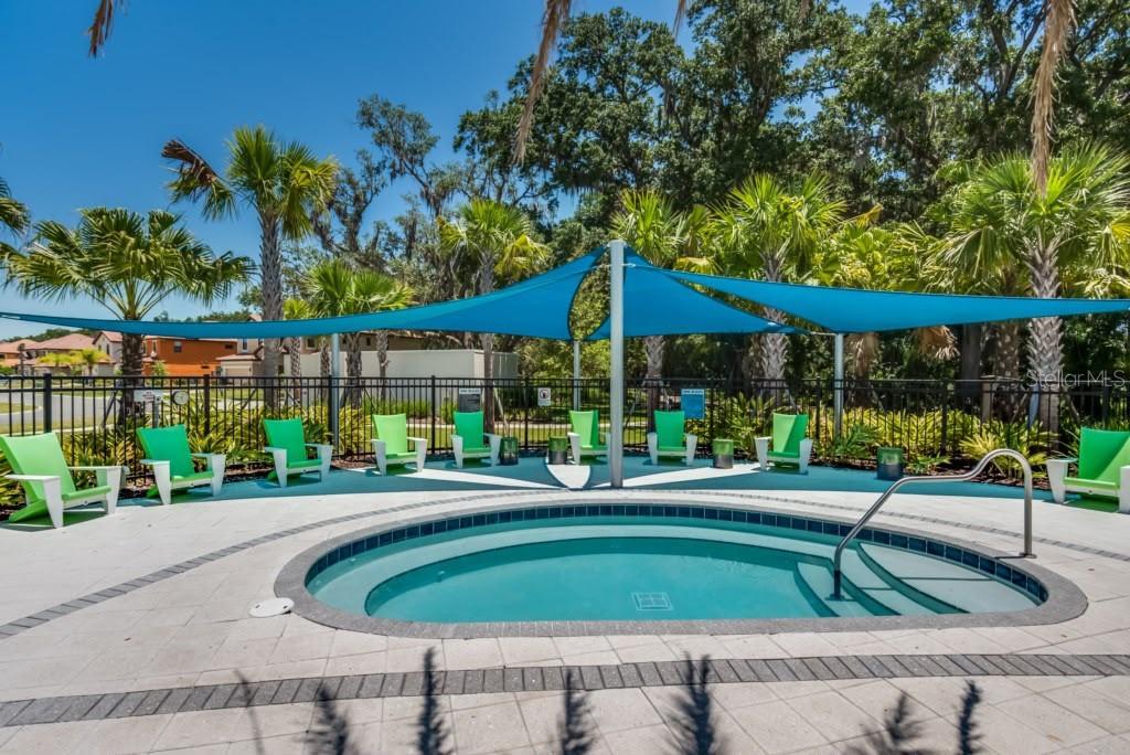A circular hot tub sits on a paved patio beneath a blue shade sail canopy — 2468 RAMA DRIVE, KISSIMMEE, FL