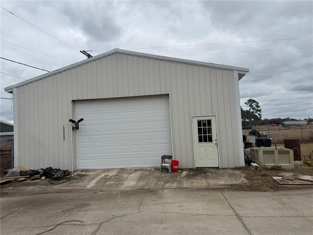 A detached metal garage with a white roll-up door and a single entry door — 3970 E KNIGHTS GRIFFIN ROAD, PLANT CITY, FL