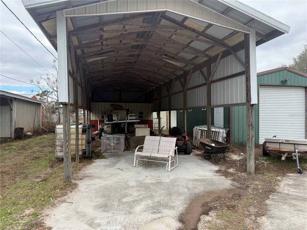 A large, open-sided metal carport sits on a concrete slab with various stored items — 3970 E KNIGHTS GRIFFIN ROAD, PLANT CITY, FL