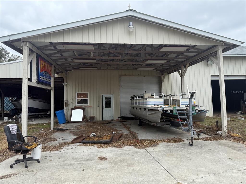 A metal-roofed carport covers a concrete area with a pontoon boat and a desk chair — 3970 E KNIGHTS GRIFFIN ROAD, PLANT CITY, FL