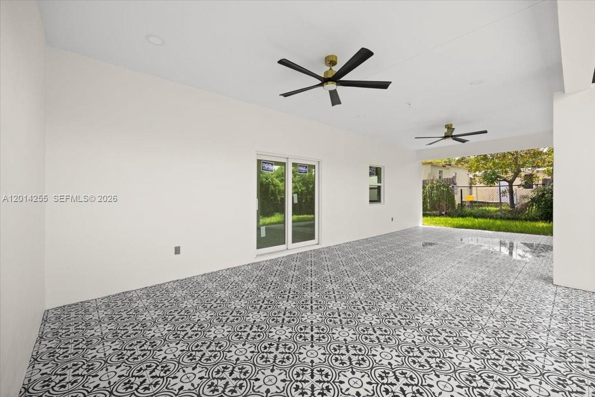 A covered patio features patterned tile flooring, white walls, and two ceiling fans — 930 34th St, West Palm Beach FL 33407, WEST PALM BEACH, FL