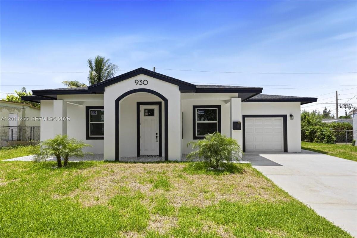 The exterior of a single-story house features a white facade, dark trim, and a garage — 930 34th St, West Palm Beach FL 33407, WEST PALM BEACH, FL