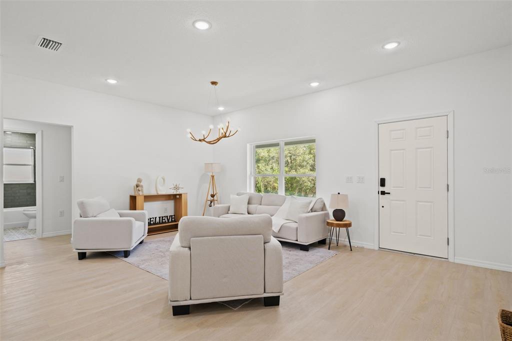 A bright living room features light wood flooring, white walls, and a modern antler chandelier — 2784 W PARAGON, CITRUS SPRINGS, FL