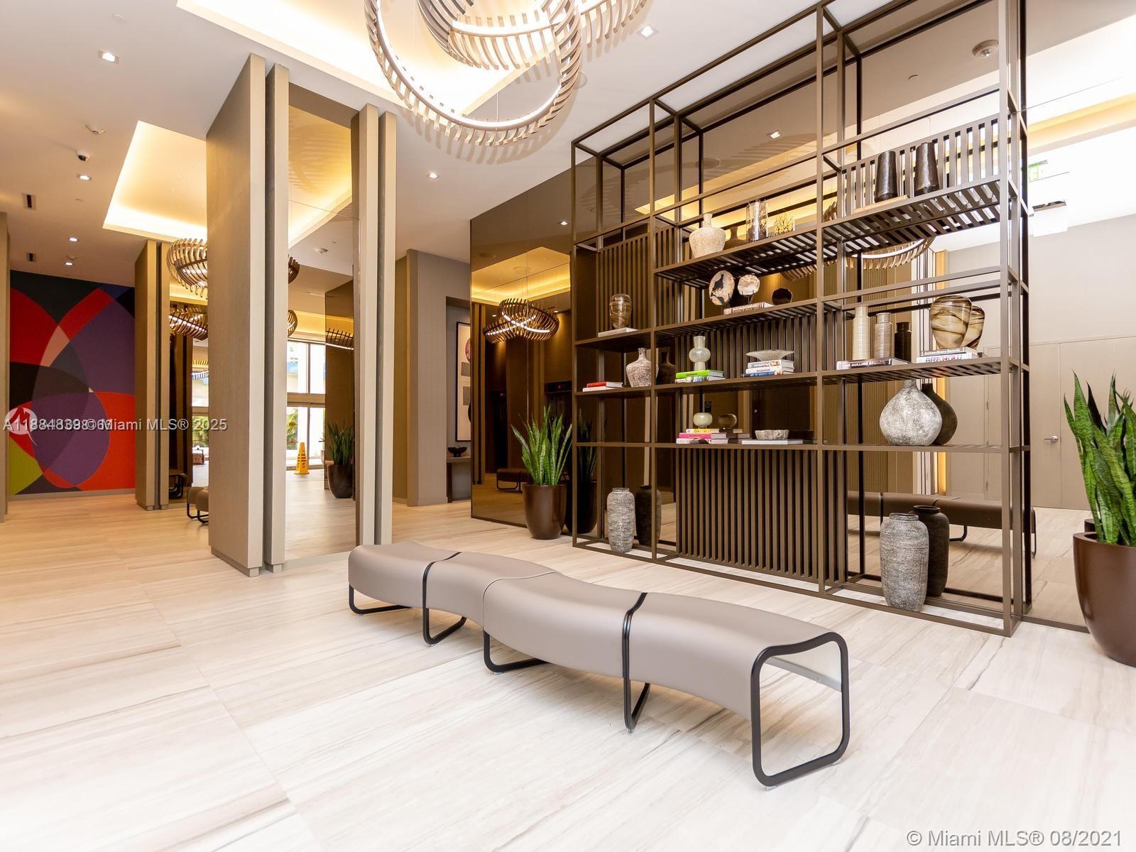 A modern lobby features a long gray bench, a large metal shelving unit, and tile flooring — 4010 S Ocean Dr # R401, Hollywood FL 33019, HOLLYWOOD, FL