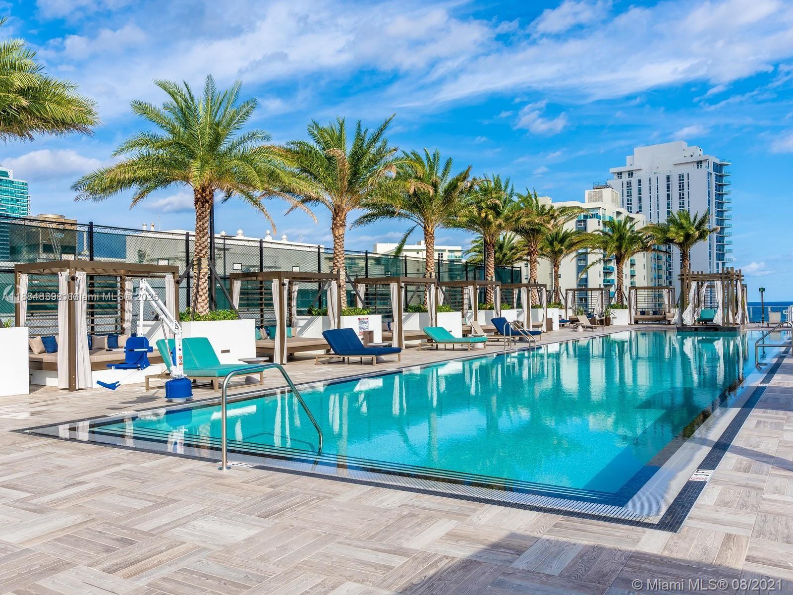 A swimming pool with lounge chairs and cabanas sits on a terrace with palm trees — 4010 S Ocean Dr # R401, Hollywood FL 33019, HOLLYWOOD, FL