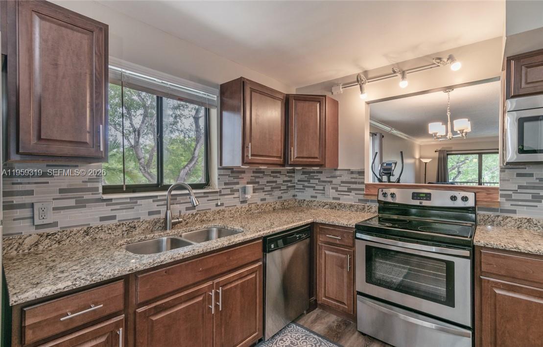 A kitchen features dark wood cabinets, granite countertops, stainless steel appliances, and a tiled backsplash — 402 Lakeview Dr # 201, Weston FL 33326, WESTON, FL