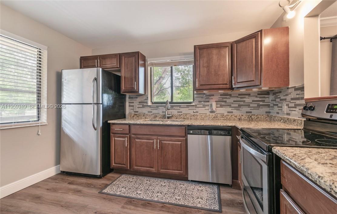 A kitchen features dark wood cabinets, stainless steel appliances, granite countertops, and a tiled backsplash — 402 Lakeview Dr # 201, Weston FL 33326, WESTON, FL