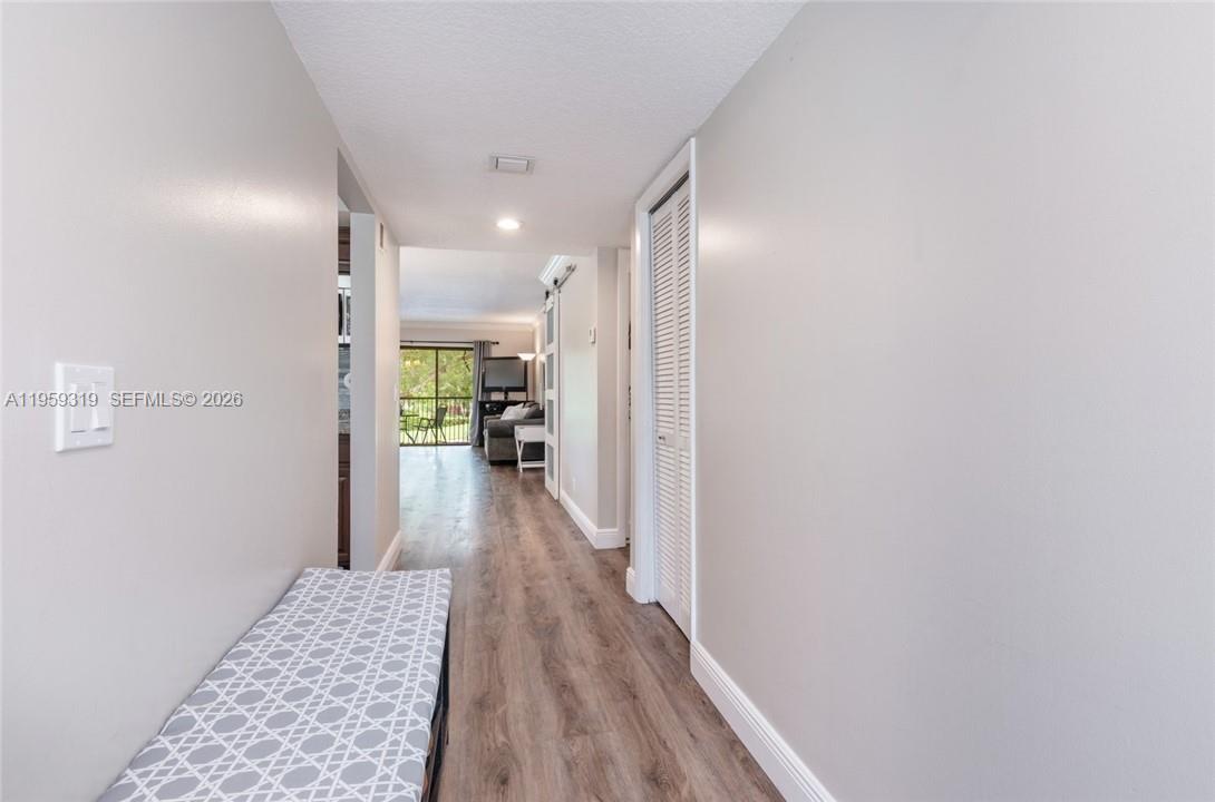 A hallway with wood-look flooring leads to a living area with a sliding glass door — 402 Lakeview Dr # 201, Weston FL 33326, WESTON, FL