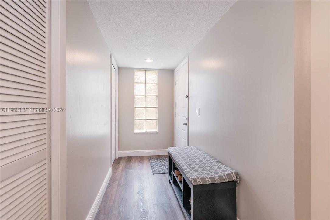 A narrow hallway features wood-look flooring, a glass block window, and a storage bench — 402 Lakeview Dr # 201, Weston FL 33326, WESTON, FL