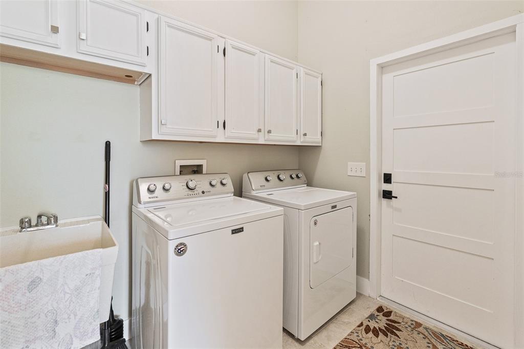 A laundry room features white cabinets, a utility sink, and a washer and dryer set — 3194 MISTY MORN COURT, ST CLOUD, FL