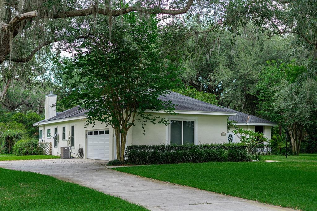A single-story house with a white exterior, a garage, and a driveway surrounded by trees — 3194 MISTY MORN COURT, ST CLOUD, FL