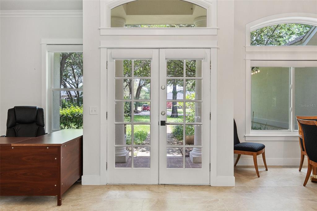 A bright room features double glass-paned doors, tile flooring, and a desk with a chair — 3194 MISTY MORN COURT, ST CLOUD, FL