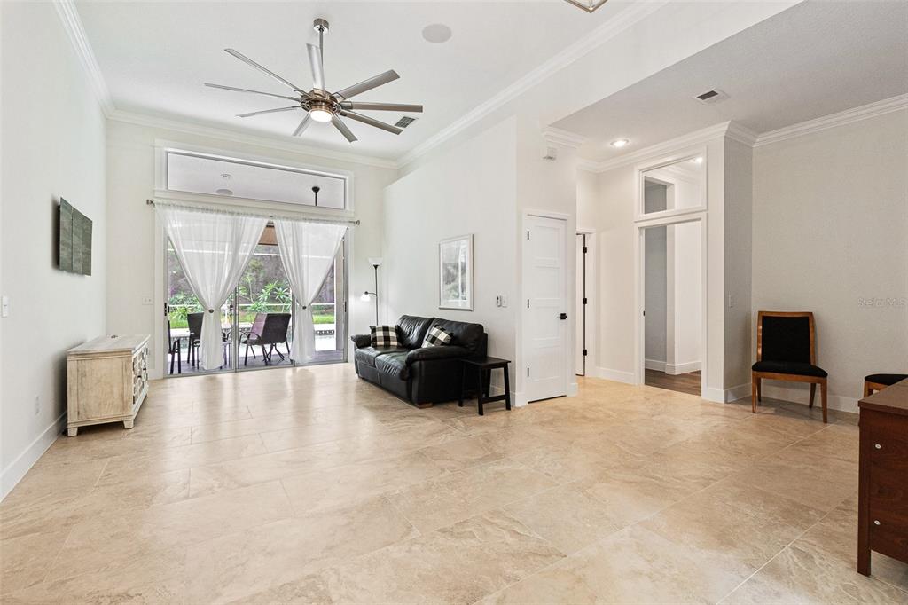 A living room features tile flooring, a ceiling fan, a black sofa, and sliding glass doors — 3194 MISTY MORN COURT, ST CLOUD, FL