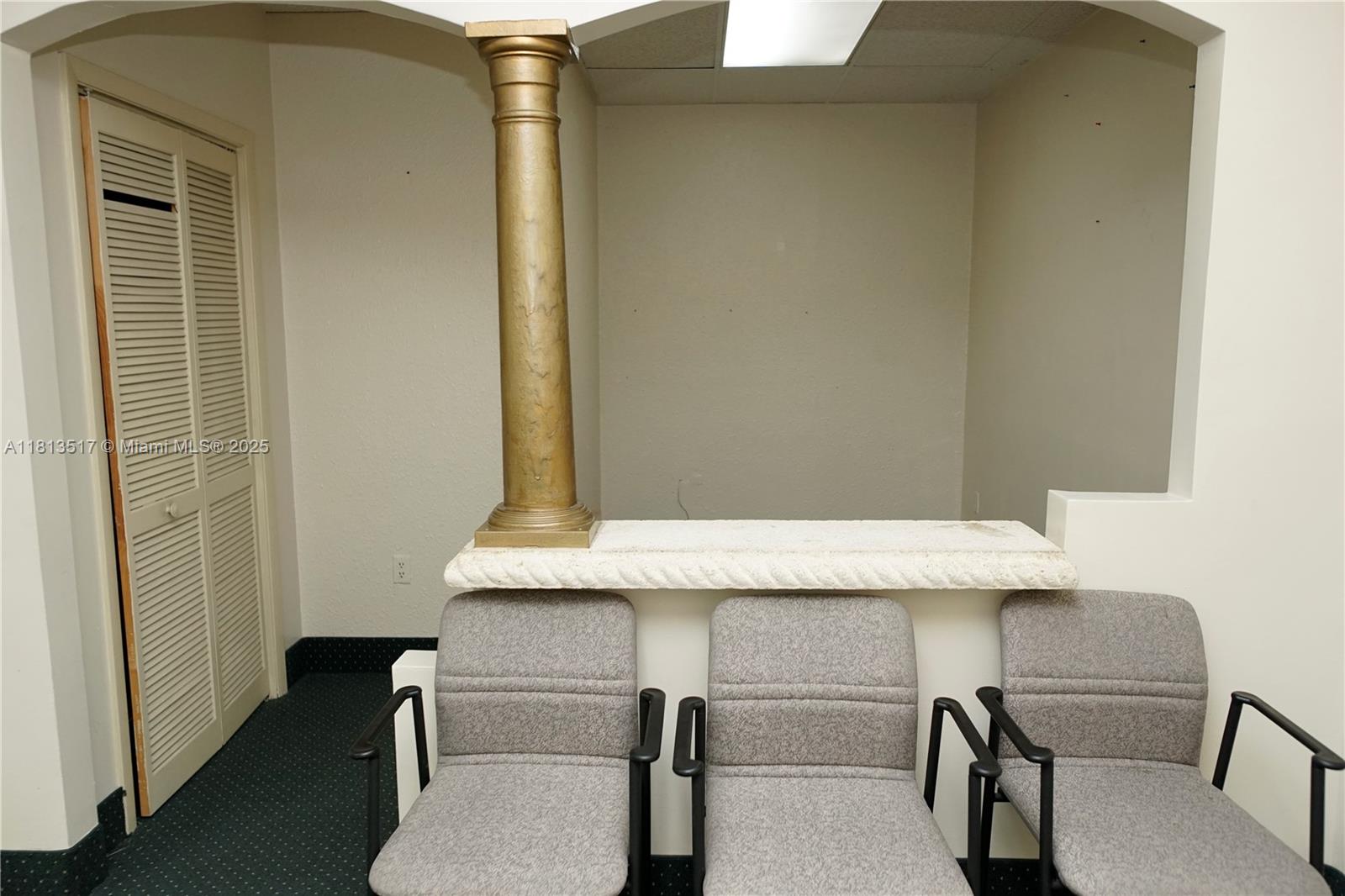 Three gray chairs sit in front of a low wall with a decorative gold column — 8500 SW 40th St, Miami FL 33155, MIAMI, FL