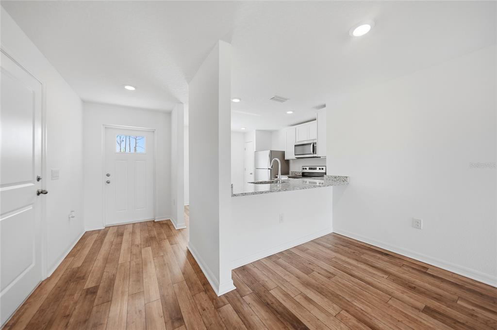 A view of an entryway leading into a kitchen with white cabinets and granite countertops — 5373 ULYSSES STREET, PORT CHARLOTTE, FL