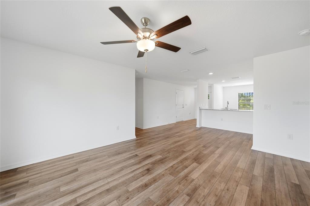 An open-concept living area features wood-look flooring, a ceiling fan, and a kitchen island — 5373 ULYSSES STREET, PORT CHARLOTTE, FL