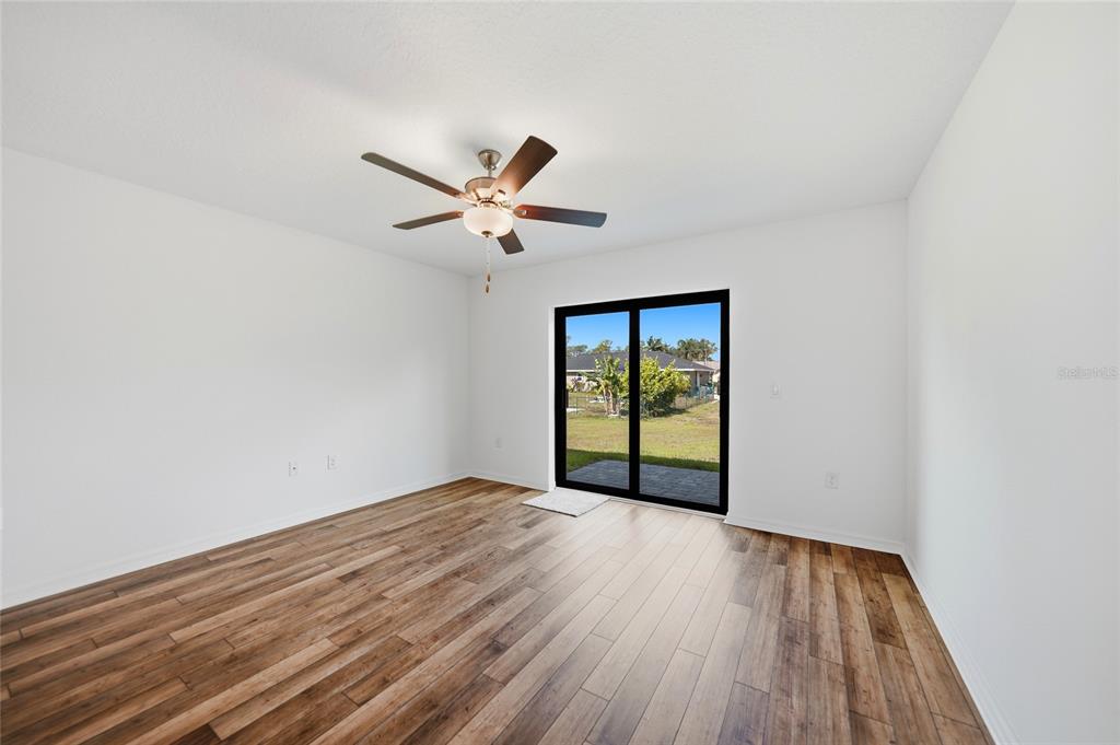 An empty room with white walls, wood-look flooring, a ceiling fan, and sliding glass doors — 5373 ULYSSES STREET, PORT CHARLOTTE, FL