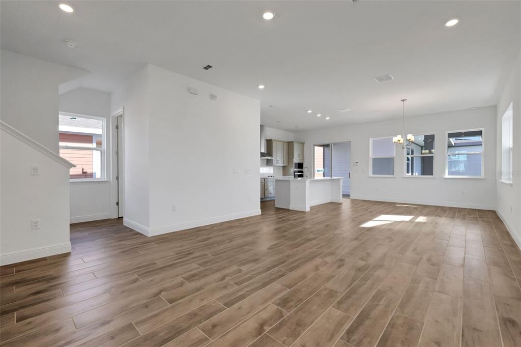 An open-concept living area features light wood-look tile flooring, white walls, and a kitchen island — 2954 SAILBOAT DRIVE, ST CLOUD, FL