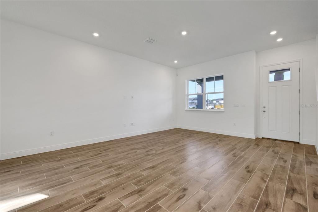 An empty room with white walls, recessed lighting, and wood-look tile flooring — 2954 SAILBOAT DRIVE, ST CLOUD, FL