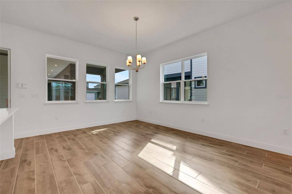 A dining area with white walls, wood-look tile flooring, a chandelier, and multiple windows — 2954 SAILBOAT DRIVE, ST CLOUD, FL