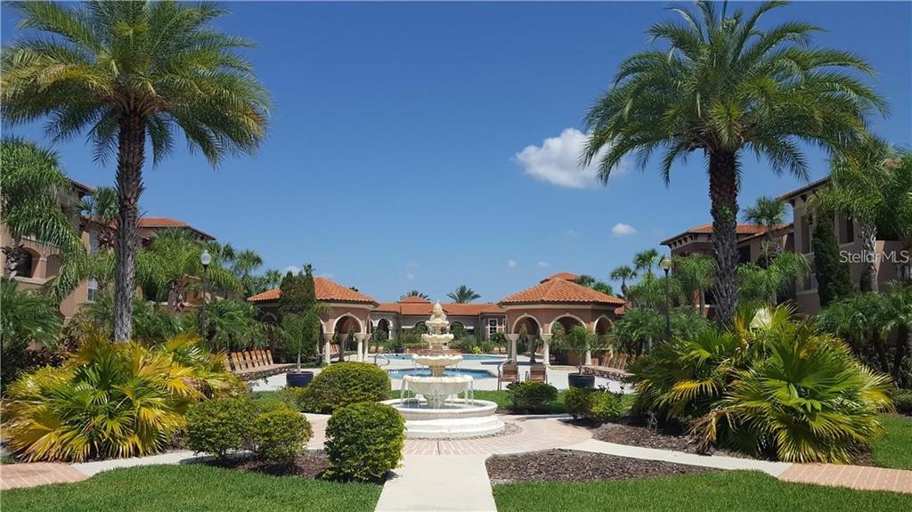 A tiered stone fountain sits in a courtyard surrounded by palm trees and apartment buildings — 5566 METROWEST BOULEVARD UNIT 303, ORLANDO, FL