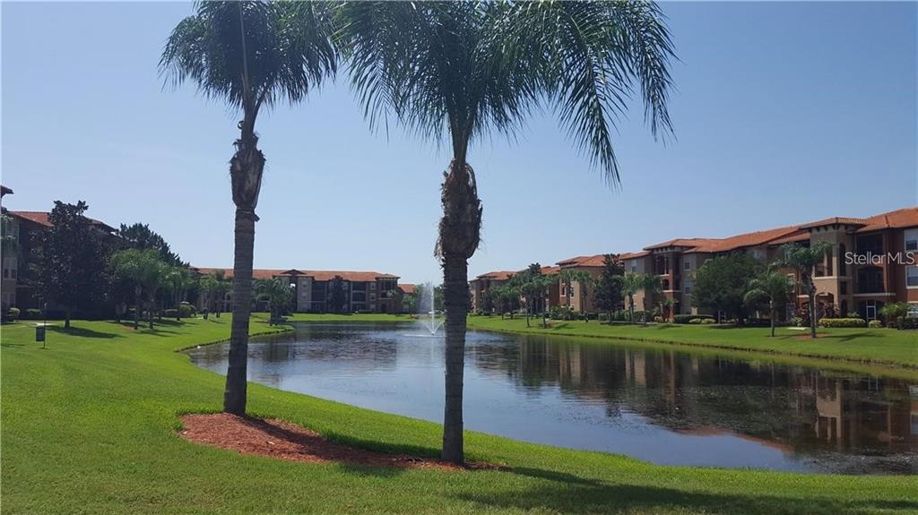 A pond with a fountain sits between apartment buildings and palm trees on a sunny day — 5566 METROWEST BOULEVARD UNIT 303, ORLANDO, FL